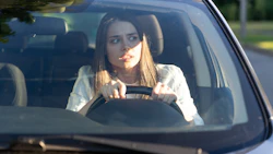 Young driver looking focused while gripping steering wheel in car