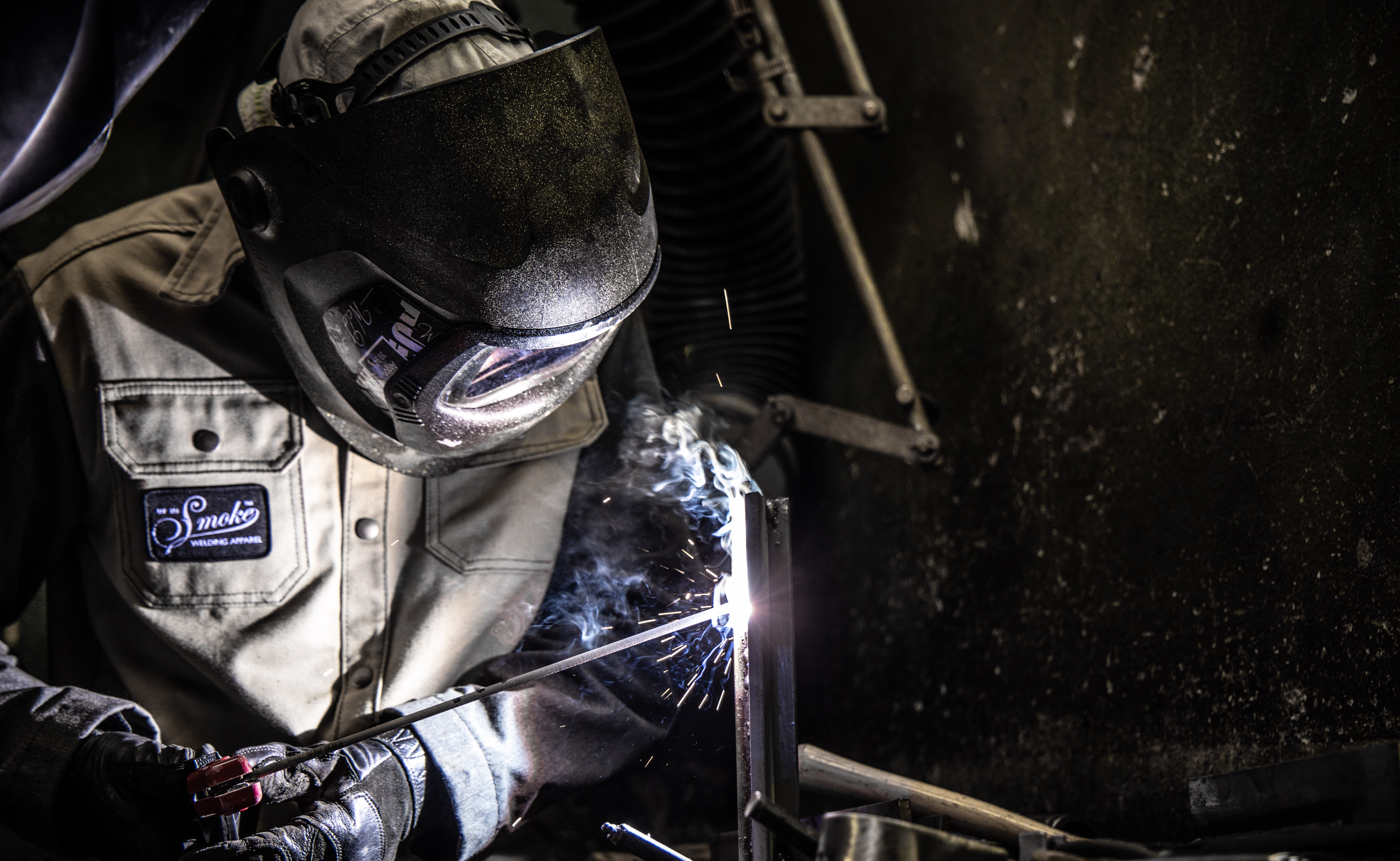 Welder in protective gear working with sparks flying during metal fabrication