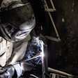 Welder in protective gear working with sparks flying during metal fabrication