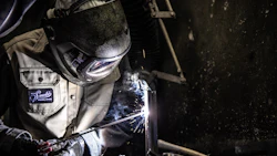 Welder in protective gear working with sparks flying during metal fabrication
