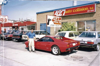Red sports car parked outside 427 Auto Collision auto repair shop with other vehicles