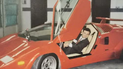 Bright red vintage sports car with scissor door open in indoor garage setting