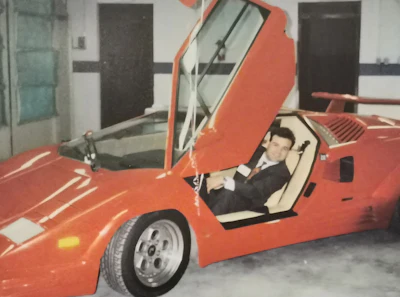 Bright red vintage sports car with scissor door open in indoor garage setting
