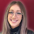 Smiling woman with glasses and freckles against burgundy background
