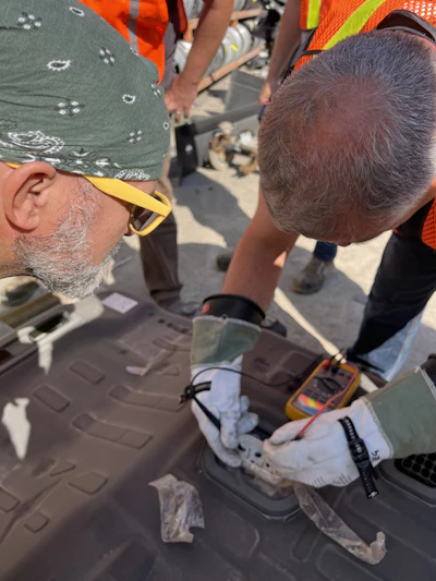 Construction workers using electrical testing equipment on site