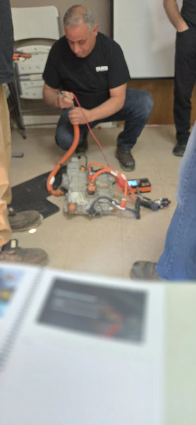 Technician crouching and working with orange-colored technical equipment in an indoor setting