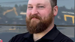 Bearded professional in black Excellence Auto Collision polo shirt
