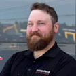 Bearded professional in black Excellence Auto Collision polo shirt