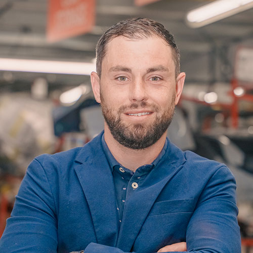 Professional in blue blazer standing in industrial workspace