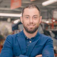 Professional in blue blazer standing in industrial workspace