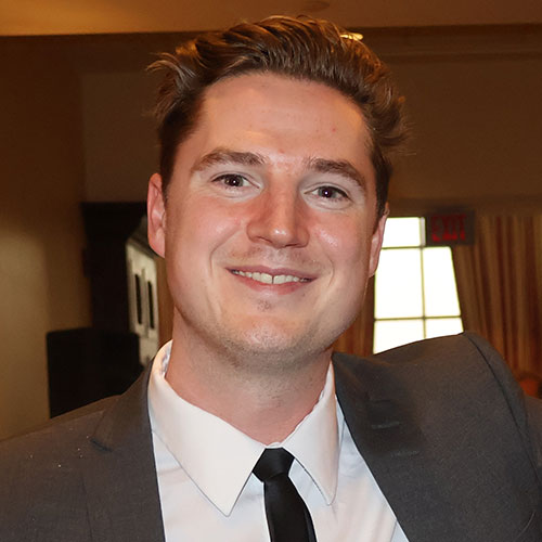 Smiling professional in gray suit and black tie at indoor event