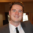 Smiling professional in gray suit and black tie at indoor event