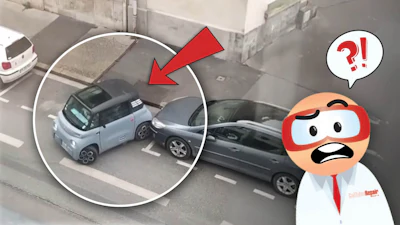 Small blue car wedged at an angle between two other vehicles in a parking area
