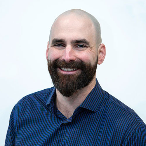 Smiling bald man with full beard wearing blue checkered button-up shirt