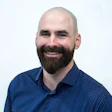 Smiling bald man with full beard wearing blue checkered button-up shirt