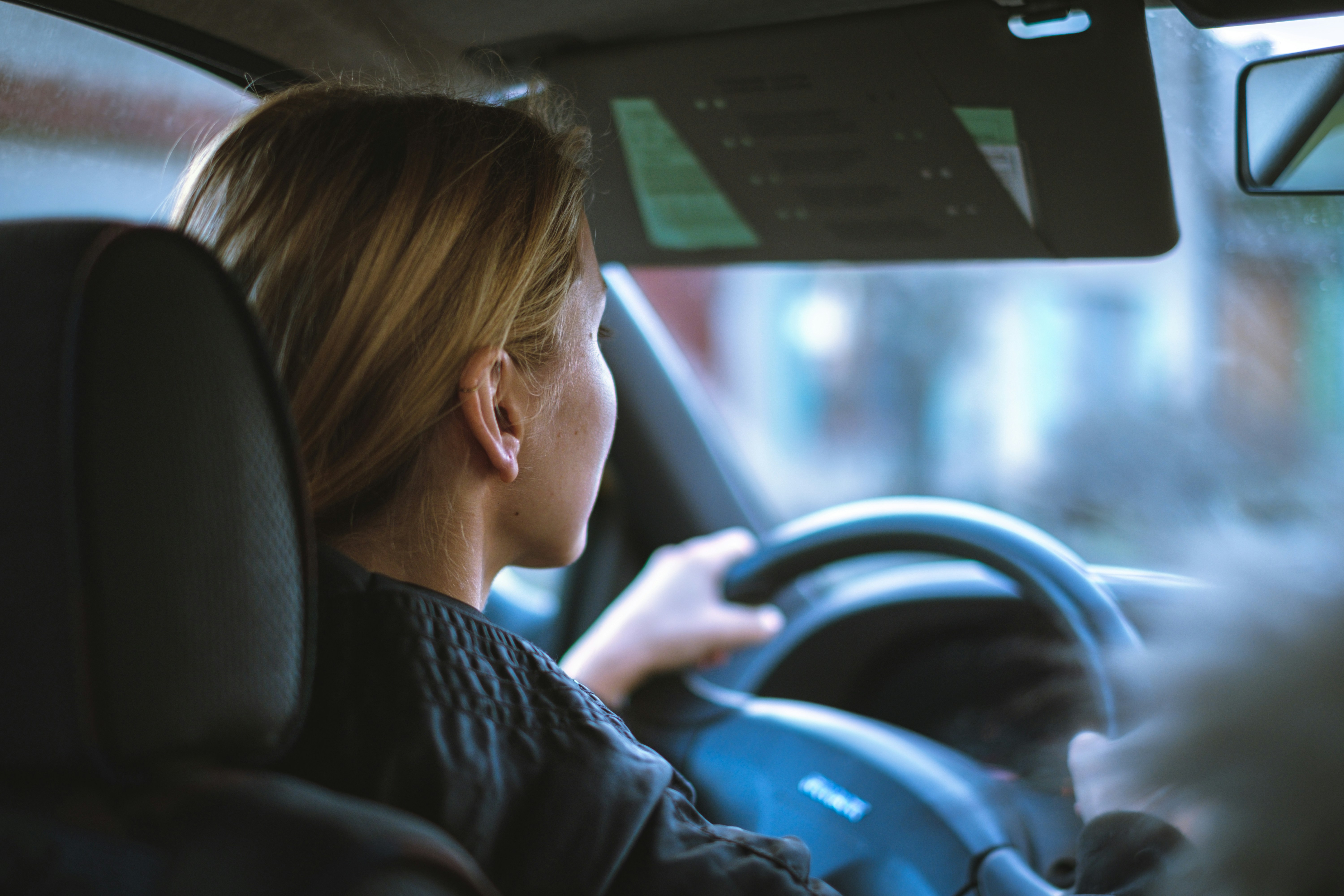 Person driving a car, viewed from behind through the vehicle's interior