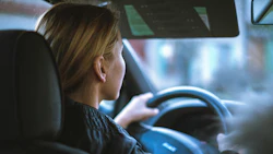 Person driving a car, viewed from behind through the vehicle's interior