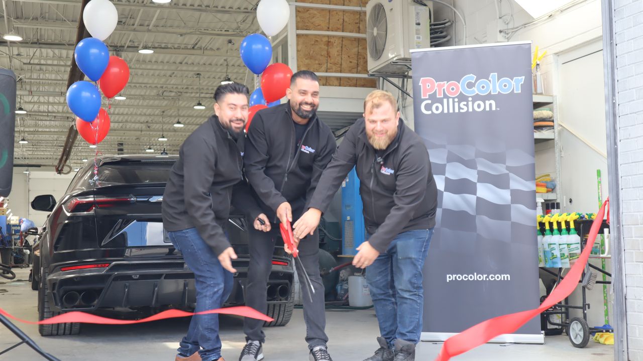 ProColor Collision ribbon-cutting ceremony with three employees and branded backdrop