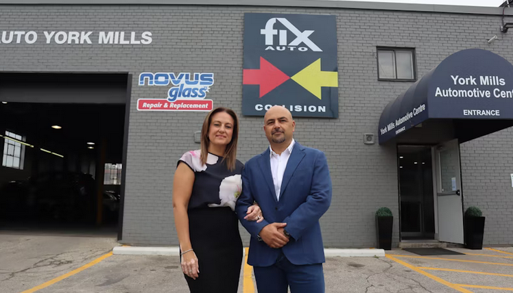 Two professionals standing in front of automotive repair and glass replacement business storefront
