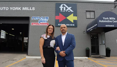Two professionals standing in front of automotive repair and glass replacement business storefront