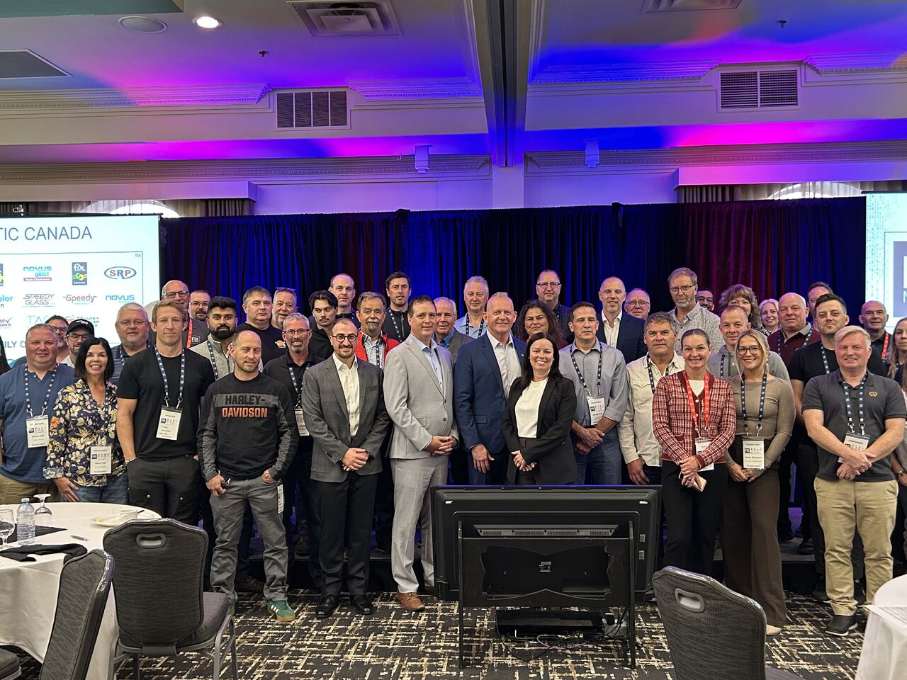 Large group of professionals gathered at an IC Canada conference event with blue and purple lighting