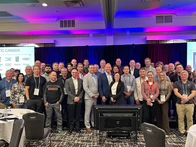 Large group of professionals gathered at an IC Canada conference event with blue and purple lighting