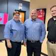 Three Hunter employees in blue and black shirts standing in an office with Canadian map display