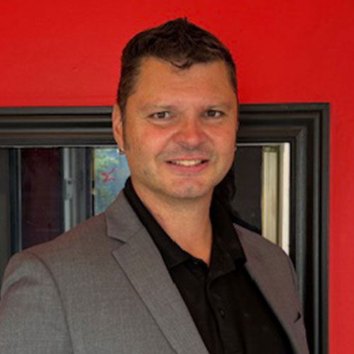 Smiling professional in gray suit against bright red background