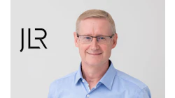 Professional headshot of a smiling middle-aged man in blue shirt with JLR logo