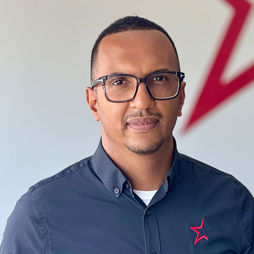 Professional man in glasses wearing navy blue button-down shirt with red star logo