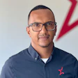 Professional man in glasses wearing navy blue button-down shirt with red star logo