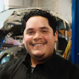 Smiling automotive technician in black shirt standing in repair shop
