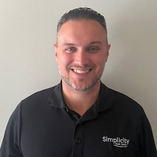 Smiling professional in black Simplicity polo shirt against neutral background
