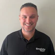 Smiling professional in black Simplicity polo shirt against neutral background