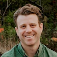 Smiling man in green shirt outdoors with trees in background