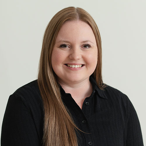 Smiling woman in black shirt with long blonde hair against neutral background