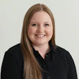 Smiling woman in black shirt with long blonde hair against neutral background