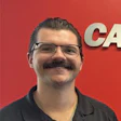 Smiling employee in glasses and black shirt against red background