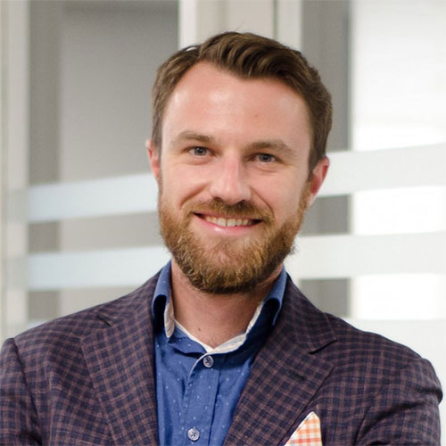Smiling professional in plaid blazer and blue shirt against white background