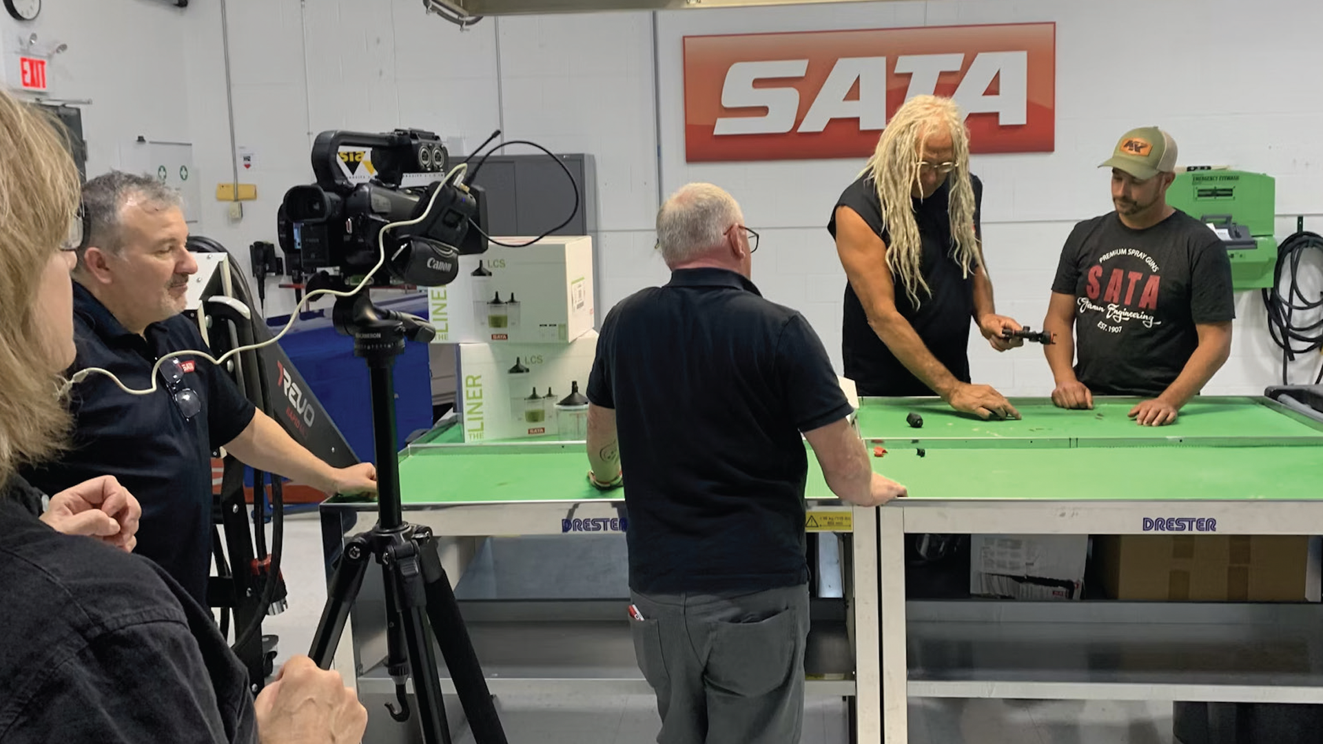 SATA video production scene with camera, green table, and team members