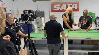 SATA video production scene with camera, green table, and team members