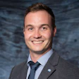 Professional smiling man in gray suit and blue tie, blurred background
