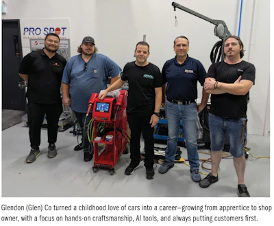 Five automotive technicians posing with diagnostic equipment in a workshop