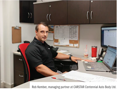 Professional in black shirt working at desk with laptop in office