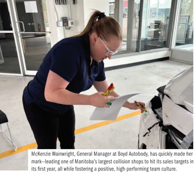 Auto body shop employee examining vehicle documentation in repair facility