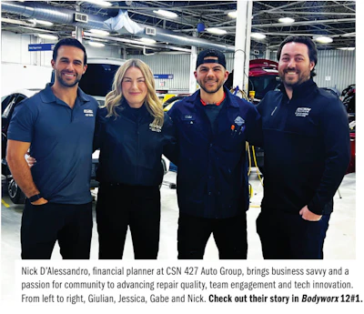 Four automotive technicians in blue uniforms standing in car repair workshop