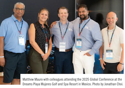 Five professionals in business attire at a conference, wearing name badges