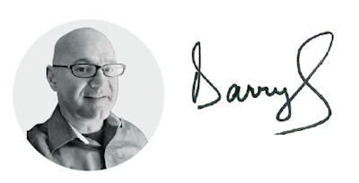 Bald man with glasses in collared shirt, next to handwritten signature