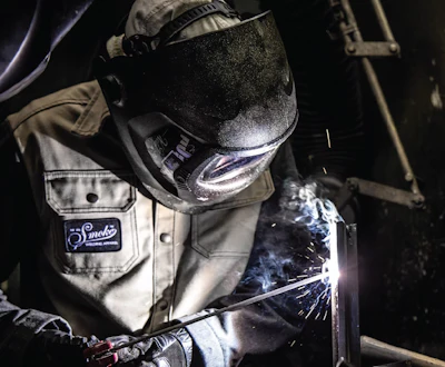 Welder in protective gear performing metal welding with sparks flying