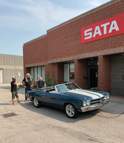 SATA logo on red brick building with classic blue convertible car parked outside